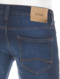 Jean en denim bleu foncé avec une étiquette en cuir sur la taille arrière, des coutures contrastées et un design de poche incurvée distinctif.
