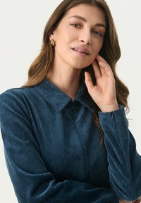 Navy Corduroy-Hemd mit Kragen, langen Ärmeln und strukturiertem Stoff mit vertikalen Rillen. Reißverschlussdetail am Ärmel.