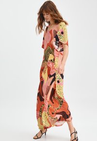 Maxikleid aus leichtem Stoff mit lebhaften abstrakten Mustern in Pink, Gelb und Schwarz. Luftige Silhouette mit weiten Ärmeln.