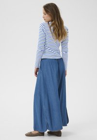 Haut à manches longues rayé en bleu et blanc, associé à une jupe en denim fluide et longue jusqu'aux chevilles. Tissu doux avec une coupe décontractée et des fentes sur les côtés.