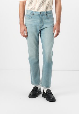 Light blue denim jeans with a straight cut and subtle fading. Features classic five-pocket design, zip fly, and a slightly distressed texture.