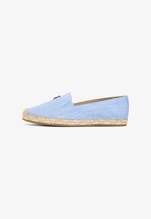 Lichtblauwe slip-on espadrille met geweven jutezool en een klein metalen logodetail op het bovenwerk, vanaf de zijkant bekeken.