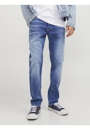 Blaue Jeans aus Denim mit einem ausgebleichten Waschgang, geradem Beinanschnitt und kontrastierenden Nähten, getragen mit marineblauen Sneakers.