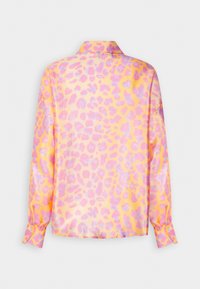Chemise à manches longues avec col, présentant un imprimé léopard rose et violet brillant sur fond jaune, vue de dos.