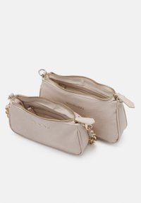 Dvě béžové kabelky Valentino, jedna menší uvnitř druhé. Obě mají texturované povrchy, zlaté zipy a řetízkové akcenty.