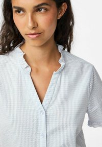 Camicia button-up azzurro chiaro in tessuto a quadretti, con colletto arricciato, maniche corte e vestibilità morbida, caratterizzata da un tessuto di cotone testurizzato.