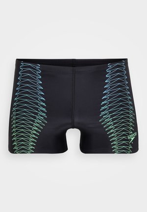 Čierne plavky s priliehavým strihom, na bokoch s modro-zeleným zigzagovým vzorom a malým logom Speedo v pravom dolnom rohu.