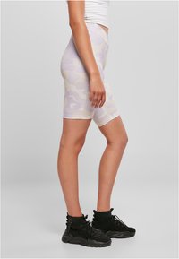 Lyse lilla og beige camouflagemønstrede cykelshorts med mellemhøj talje og glat tekstur, kombineret med sorte høje atletiksko.