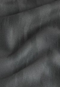 Schwarzer Stoff mit glatter Textur, der subtile Farb- und Glanzvariationen aufweist und ein weiches, fließendes Erscheinungsbild erzeugt.