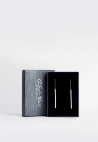 Orecchini a goccia color argento con design a barra allungata, presentati in una scatola rivestita in velluto nero con un'esterno argentato testurizzato.
