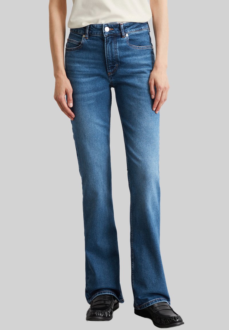 Blauwe vloeiende jeans met een vervaagde was, vijf zakken ontwerp en gestikte details. Voorzien van een knoopsluiting en riemlussen.