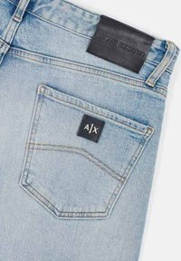 Jeans in denim azzurro chiaro con etichetta in pelle nera sulla vita e una tasca posteriore con un patch rettangolare nero che mostra "A/X".