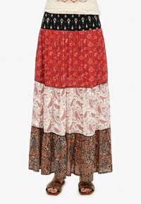 Lange bohemienrok met vier lagen: rood met bloemen, zwart met patronen, wit paisley en donkere stof met ingewikkelde ontwerpen.