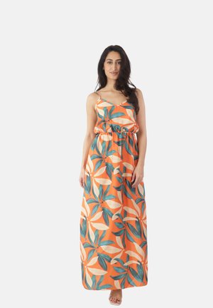 Mujer de pie con un vestido largo sin mangas color naranja con un gran estampado floral azul y beige, de ajuste holgado y tirantes finos sobre un fondo blanco.