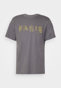 Šedé tričko s krátkým rukávem a žlutě orámovaným nápisem "PARIS" a malými technickými designovými prvky na hrudi.