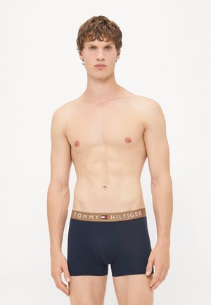 Navyblaue Baumwoll-Boxershorts mit einem braunen Gummibund, der das Logo "TOMMY HILFIGER" und ein kleines Flaggenemblem trägt.