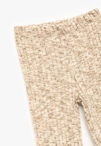 Beige, gerippte Leggings aus weichem Material, mit einem strukturierten Muster und einem elastischen Bund ohne sichtbare Nähte.