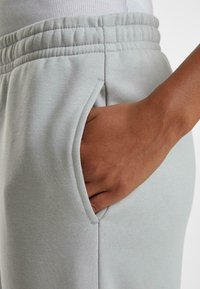 Lys grå joggershorts laget av myk stoff, med elastisk midjebånd, side lommer og en avslappet passform.