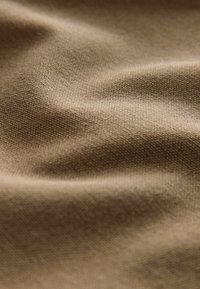 Brown fabric with a textured weave, displaying soft waves and subtle shine, showcasing a smooth yet slightly coarse finish.