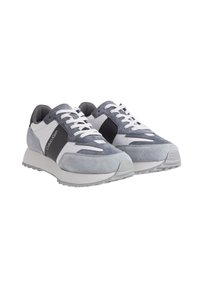 Zapatillas de ante gris y malla blanca con acentos en negro, cuentan con una suela acolchada, diseño de cordones y un logotipo visible en el lateral.