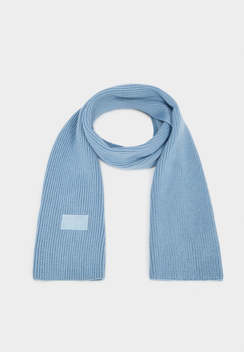 Hellesblaues geripptes Strickschal mit einem rechteckigen Akzentpatch, das eine weiche Textur und ein langgezogenes, schmales Design aufweist.