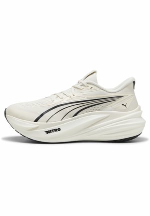 Baskets de course beige clair avec semelle épaisse, bandes logo Puma noires sur les côtés, et texte "NITRO" sur la semelle intermédiaire.