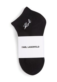 Mustat nilkkasukat, joissa on valkoista "Karl"-kirjontaa ja valkoinen pakkausnauha, johon on painettu "KARL LAGERFELD" mustalla fontilla.