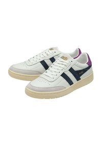 Zapatillas de cuero blancas con rayas navy, una puntera de gamuza gris claro y un acento púrpura en el talón. Detalle del logo dorado en el costado.