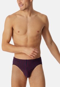 Marineblau und rot geringelte Herrenunterwäsche, gefertigt aus weichem Stoff, mit enganliegendem Schnitt und glatter Textur. Mit einer mittelhohen Taille und minimaler Bedeckung.