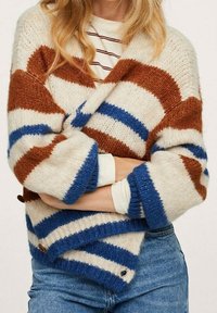 Sweter z prążkowanej dzianiny w kolorach kremowym, brązowym i niebieskim. Posiada przytulną teksturę, szerokie rękawy oraz guziki u dołu. Idealny do noszenia w warstwach.