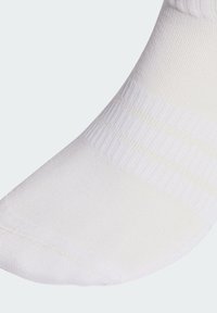 Calcetín deportivo blanco con textura acanalada, talón y punta reforzados, acabado liso y detalle sutil de rayas.