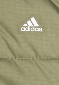 Tessuto Adidas verde oliva con motivo a griglia, caratterizzato da un logo bianco prominente e una texture liscia e leggera.
