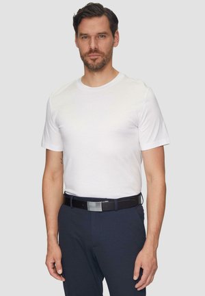 Witte t-shirt met korte mouwen gedragen met navy broek, aangevuld met een donkere riem met een zilveren gesp, wat een eenvoudige en verzorgde uitstraling biedt.