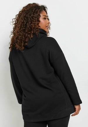 Sweatshirt à capuche noire en tissu doux, présentant une coupe décontractée, des poignets et un ourlet côtelés, avec une texture lisse et un minimalisme dans les détails.