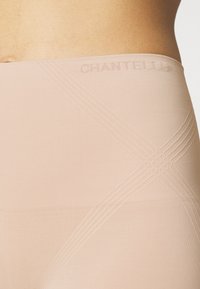 Bež krema visoki oblikovni donji dio s teksturiranim materijalom, ukriženim detaljem i utisnutim logotipom branda duž struka.
