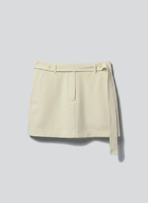Μίνι φούστα σε κρεμ απόχρωση με υφασμάτινη ζώνη, θηλιές για τη ζώνη και πλαϊνές τσέπες, απλωμένη επίπεδη σε ανοιχτό γκρι φόντο.