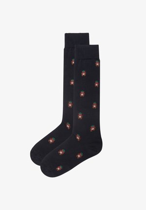 Chaussettes bleu marine foncé en tissu doux avec un motif de ours à répétition portant un chapeau vert, ajoutant une touche ludique à cette couleur classique.