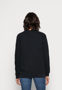 Sudadera negra con cuello redondo, puños y dobladillo acanalados. Tejido suave, corte relajado y textura lisa. Sin patrones ni logotipos visibles.