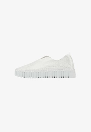Zapatilla blanca sin cordones con parte superior texturizada y suela gruesa y estriada. Cuenta con una pestaña trasera para facilitar el uso. Diseño suave y minimalista.
