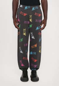 Zwarte joggingsbroek met een multikleurig cartoonkonijnenpatroon. Elastische tailleband en boorden. Gekozen in combinatie met zwarte sneakers.