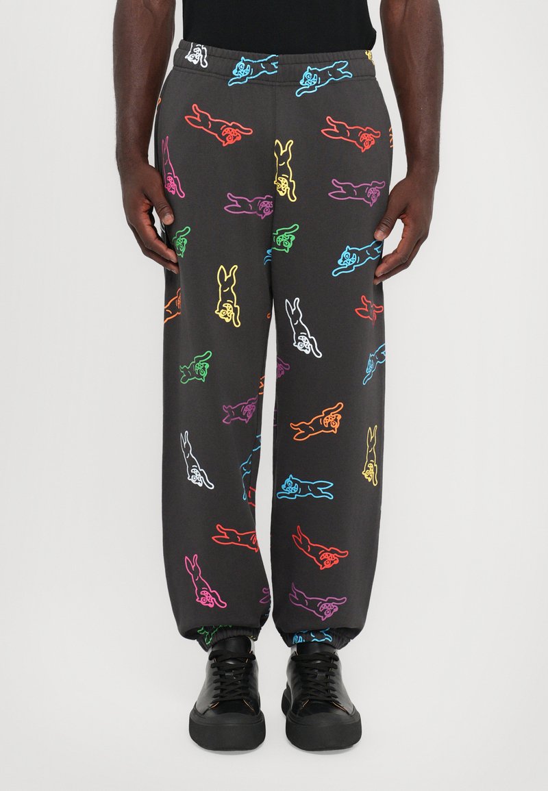 Zwarte joggingsbroek met een multikleurig cartoonkonijnenpatroon. Elastische tailleband en boorden. Gekozen in combinatie met zwarte sneakers.
