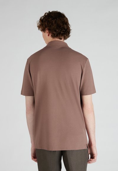 Bruine korte mouwen polo met een rechte zoom en zijsplitten, gemaakt van zachte katoenstof. De achterkant toont een relaxte pasvorm.