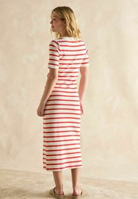 Gestreiftes Midikleid in Creme mit roten horizontalen Streifen, kurzen Ärmeln, Rundhalsausschnitt und lässiger Passform, kombiniert mit leichter Fußbekleidung.