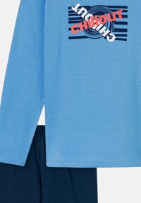 Light blue long-sleeve shirt with "CHILL OUT" graphic in red and navy, paired with dark navy shorts featuring an elastic waistband.