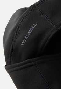 Svart tekstil med glatt tekstur, med "WINDWALL" trykt i grått. Designet inkluderer sømmer og en passform som passer til utendørs bruk.