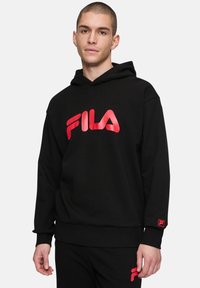 Sudadera negra hecha de tejido suave, con un gran logo rojo de FILA en el frente y un pequeño logo rojo en el puño. Corte clásico con capucha.