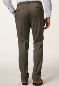 Braune Hose mit elastischem Bund, flachem Frontdesign, zwei Gesäßtaschen, glatter Textur und taillierter Passform, kombiniert mit braunen Dressschuhen.