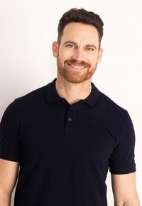 Námornícky modré polo tričko vyrobené z bavlny. Má klasický golier, krátke rukávy a zapínanie na tri gombíky. Hladká textúra.