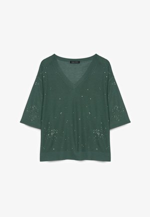 Grüner V-Ausschnitt Pullover mit kurzen Ärmeln und kleinen verstreuten silbernen Nieten, die Blumenmuster auf Vorderseite und Ärmeln bilden.