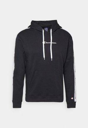Schwarzer Champion-Hoodie mit weißen Kordeln, Logo auf der Brust, gebrandete Streifen entlang der Ärmel und Kängurutasche vorne.